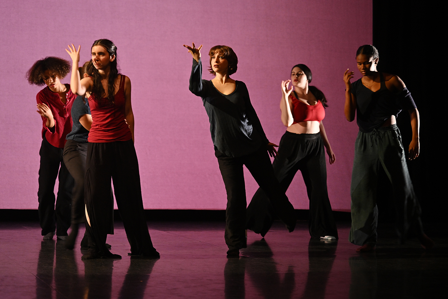 A row of dancers in red and black strike poses as the perform on stage.